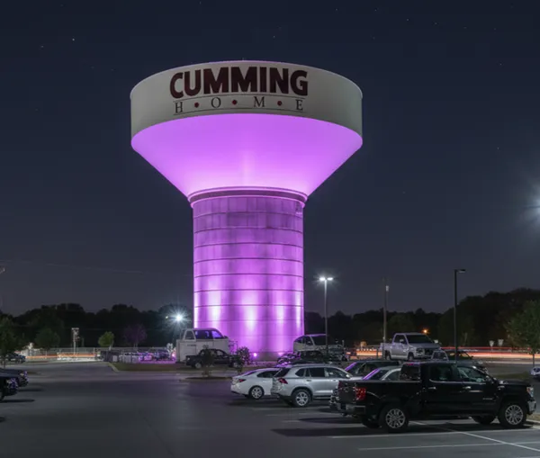 Cumming GA water tower glowing purple in a parking lot.